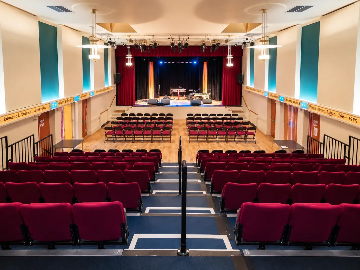 Rows of red seats and a central aisle looking towards the stage at Thornton Little Theatre